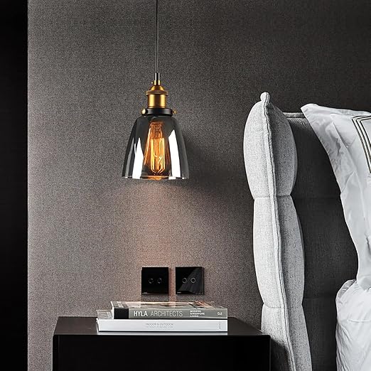Calia Suspension Cloche en Verre, Douille Laiton – suspension en verre fumé près d'un mur gris et de coussins