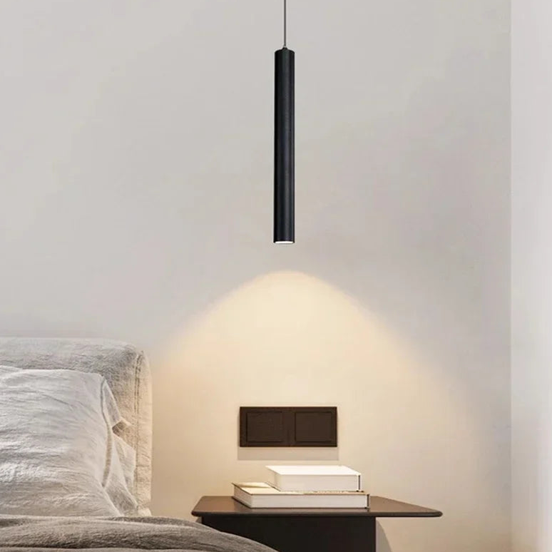 Filin Suspension Tube LED – tube noir suspendu au-dessus d'une table de chevet, cône de lumière chaude