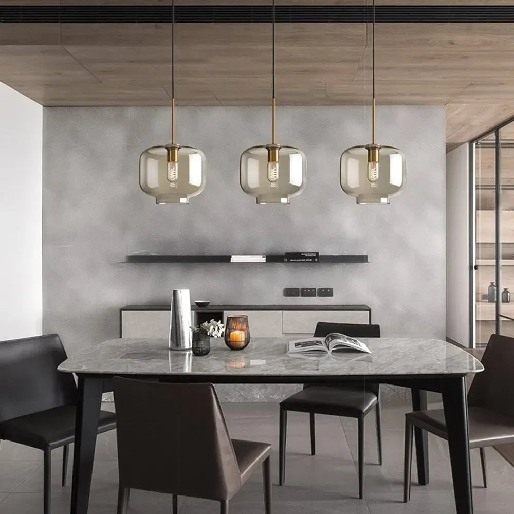 Ambra Suspension en Verre Ambré, 5 Formes au Choix – trois suspensions au-dessus d'une table devant un mur gris