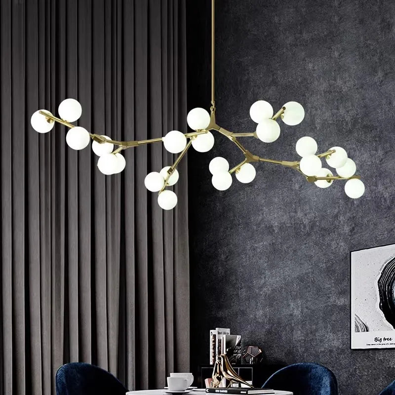 Ramure Lustre Branches à Globes Lumineux – branches dorées et globes blancs devant un rideau gris et un mur sombre