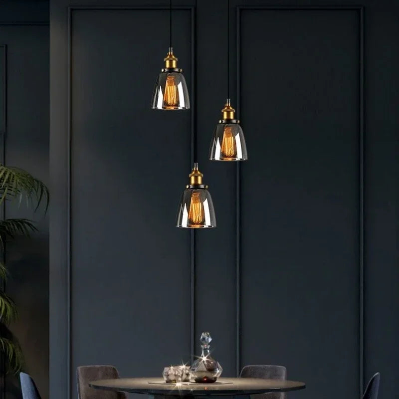 Calia Suspension Cloche en Verre, Douille Laiton – trois suspensions à hauteurs différentes devant un mur bleu nuit