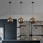 Platine de Plafond 3 Sorties, Ronde ou Linéaire – suspensions globes en verre fumé devant un mur gris