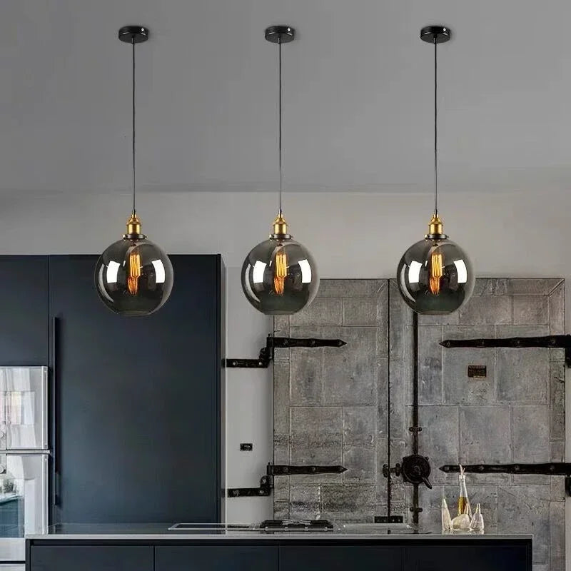 Orvane Suspension Globe en Verre, Douille Laiton – trois globes en verre fumé devant une cuisine sombre