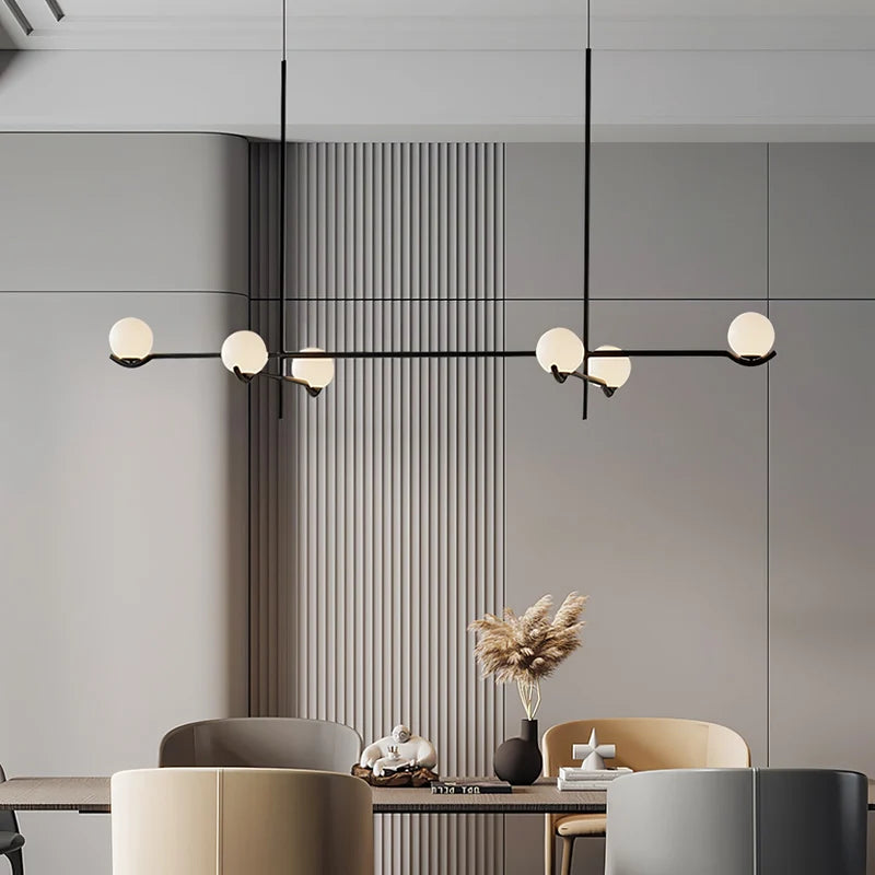 Perla Lustre à Globes en Verre – devant un mur à lattes avec branche décorative