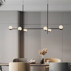Perla Lustre à Globes en Verre – devant un mur à lattes avec branche décorative