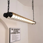 Tubia Suspension Tube en Verre Style Industriel – tube noir à cage devant une affiche murale