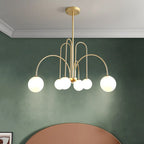 Arcadie Lustre à Bras en Arc – version dorée devant un mur vert foncé