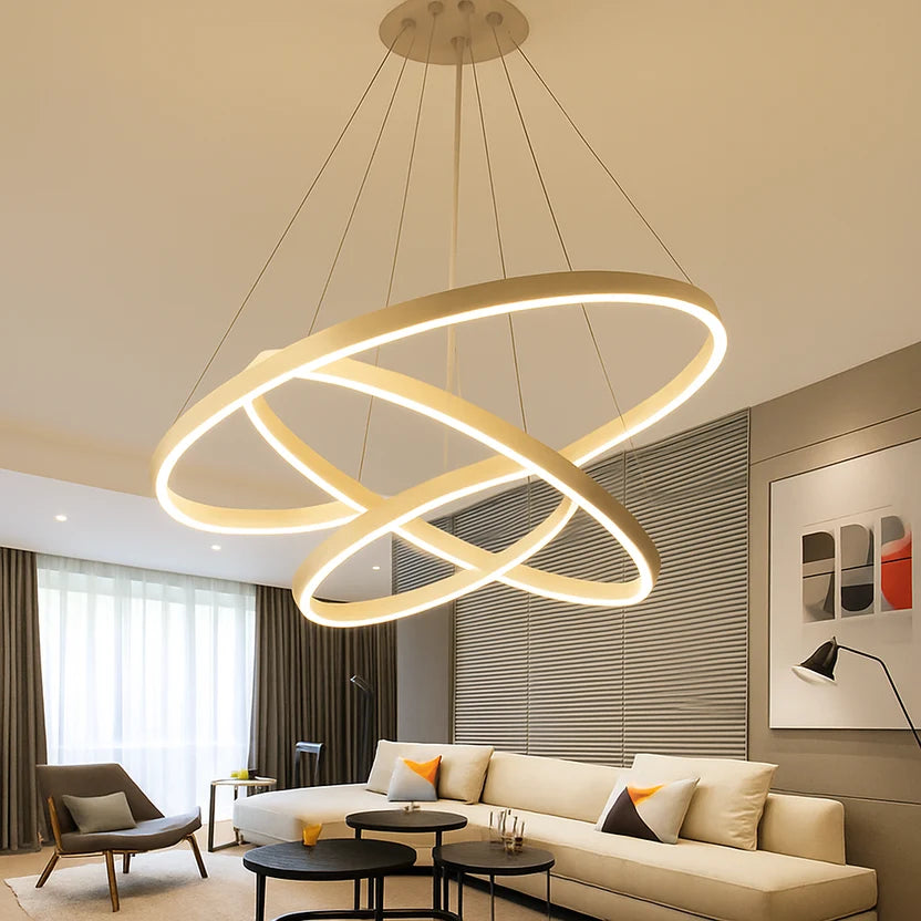 Orbite Suspension LED à Anneaux – anneaux dorés dans un salon aux rideaux sombres
