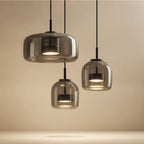 Trilia Suspension Trio en Verre, Ambré ou Fumé, sur Platine Ronde – gros plan des suspensions en verre fumé sur fond beige