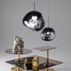Lavane Suspension Globe en Verre Fondu Irrégulier – globe sombre au-dessus d'une table avec sculpture