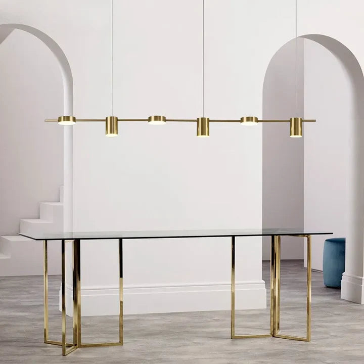 Tubo Suspension Linéaire à Spots – version dorée au-dessus d'une longue table blanche
