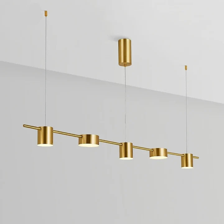 Tubo Suspension Linéaire à Spots – tubes dorés alignés en diagonale devant un mur blanc